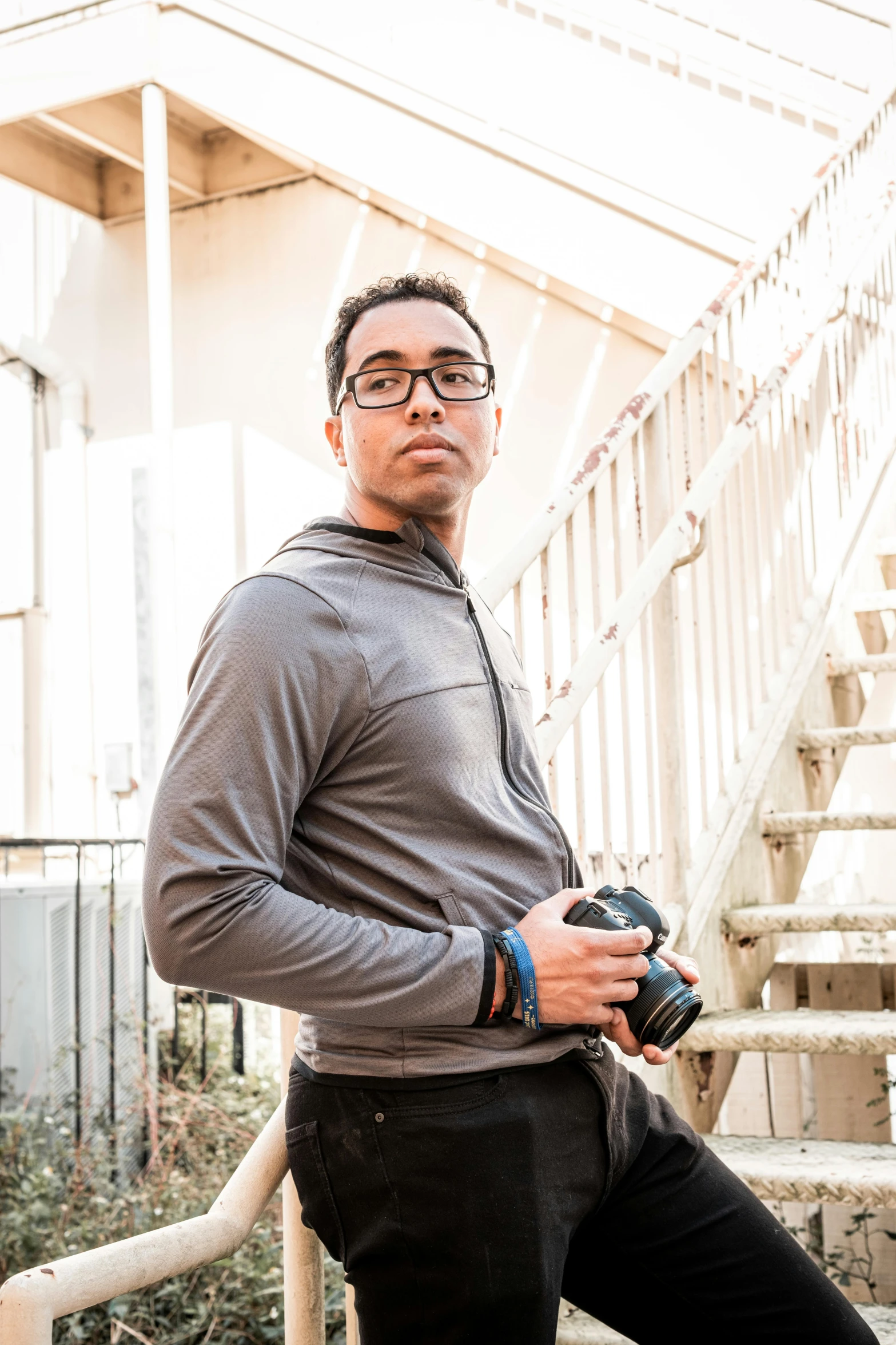 man posing on steps, while holding a camera