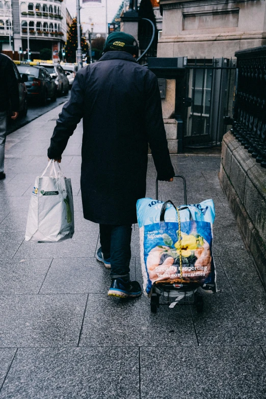 a man carrying bags and carrying a bag down a sidewalk