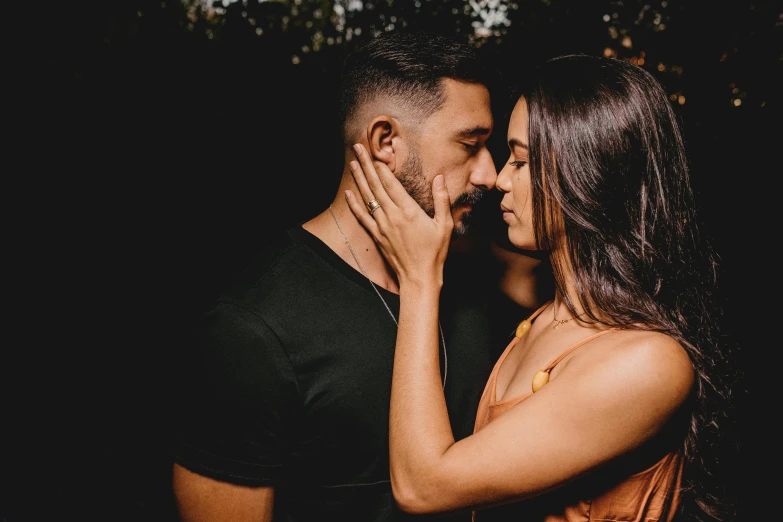 a man and woman are kissing outside by trees