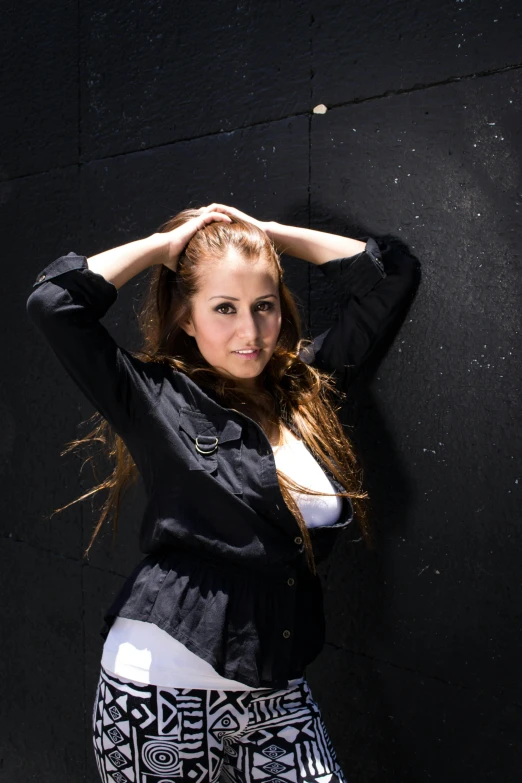 a beautiful young woman posing by a black wall