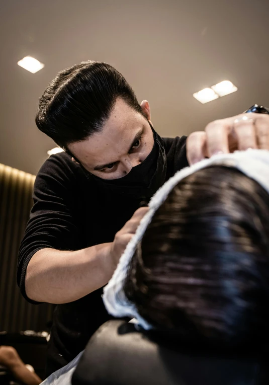 the hair stylist is drying the male customer's hair