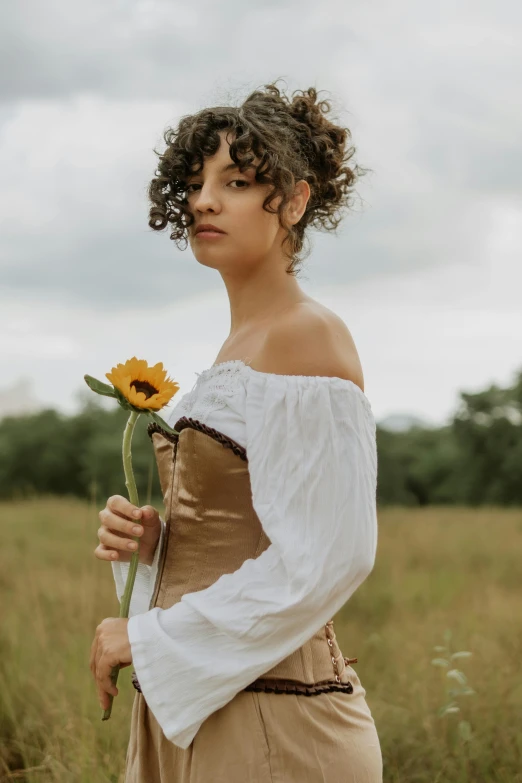 a woman with a sunflower on her shoulder in the grass