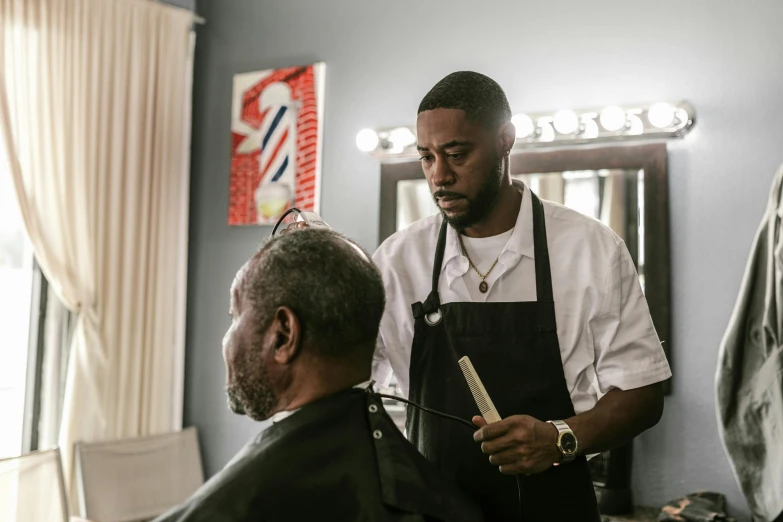 a man sitting next to a barber in front of a mirror