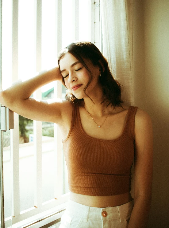 woman standing beside a window with her head near the window