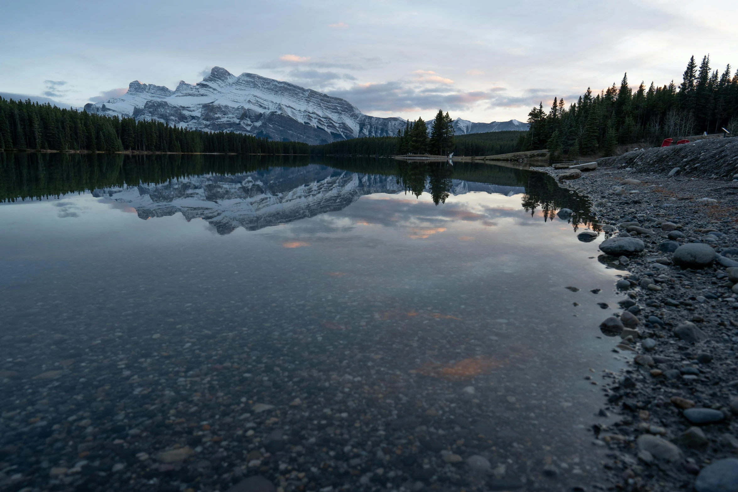 the sun is setting on a small mountain lake