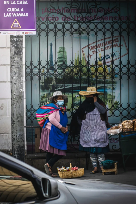 three people dressed in mexican style clothing and hats on the sidewalk