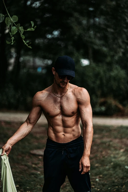 a shirtless male in shorts and  holding onto a green umbrella