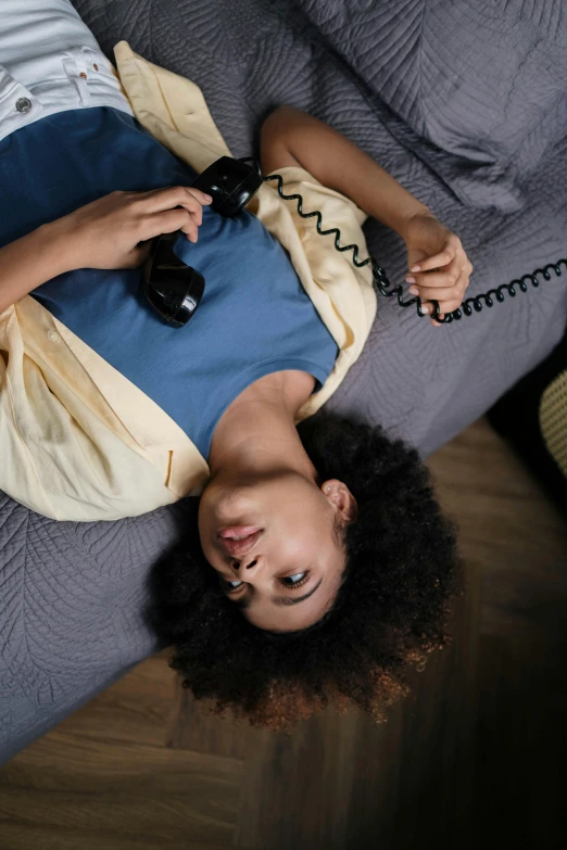 a person laying down on a bed and holding an old phone