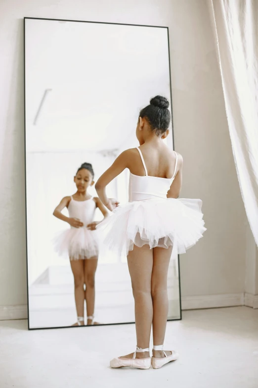 a girl with a white skirt looking at her reflection in the mirror