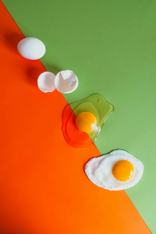 two eggs and two pieces of meat on a green orange and red background