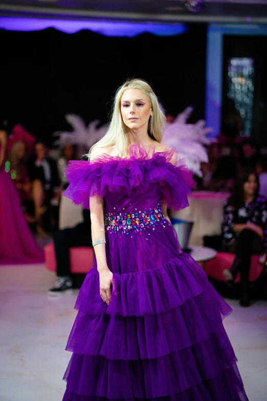 a woman in purple gown with ruffles at a fashion show