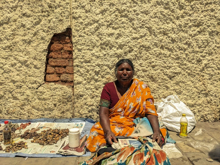 a woman sits on the ground in front of a food vendor