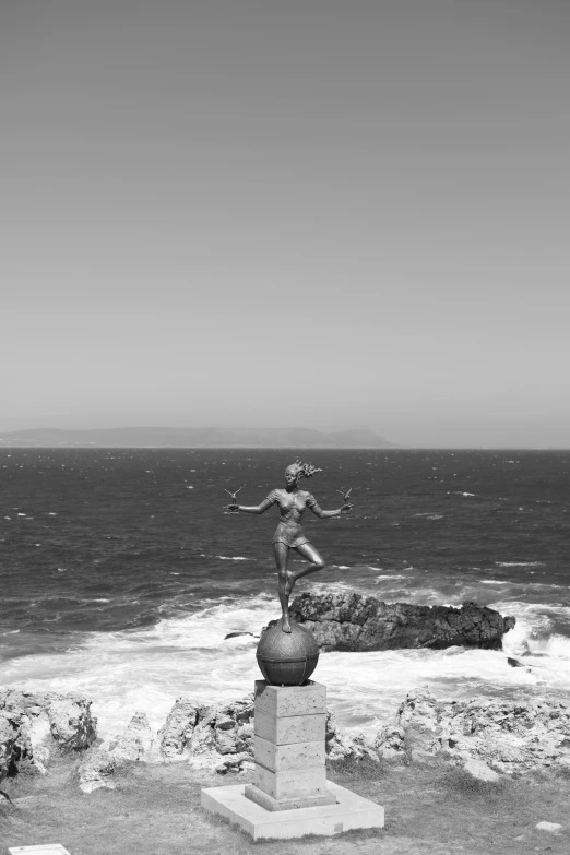 black and white image of the back side of a sculpture with rocks, water and water behind it