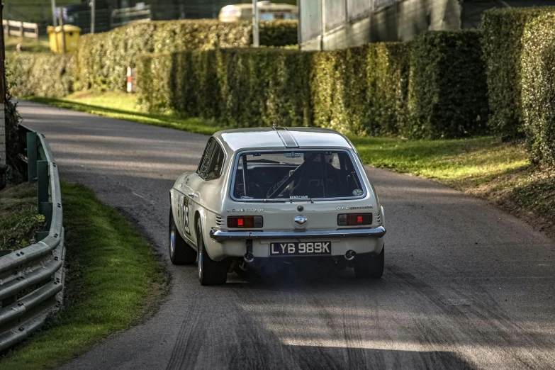 a small white car driving down a curvy road