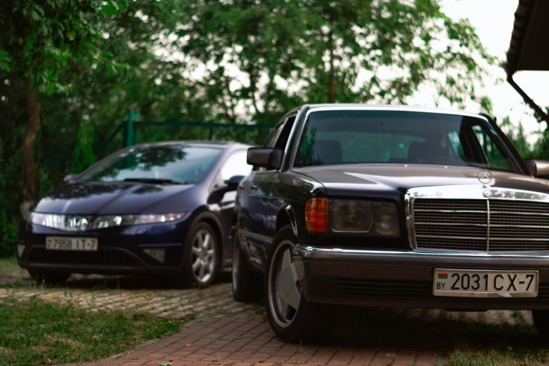 two cars parked side by side in front of some trees