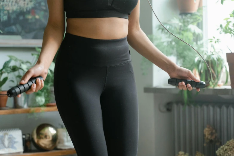 a  wearing black and has her hands behind her back while holding a video game controller