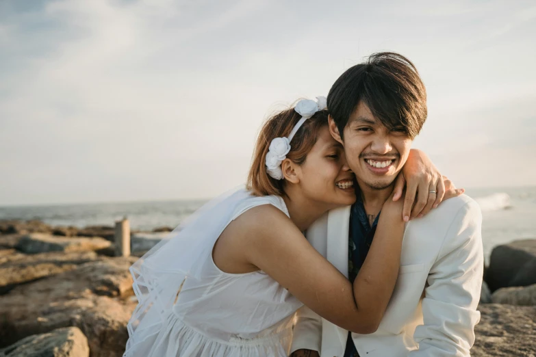 a couple posing together next to the ocean