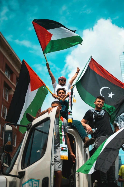 a group of men with flags and signs sitting on top of a truck