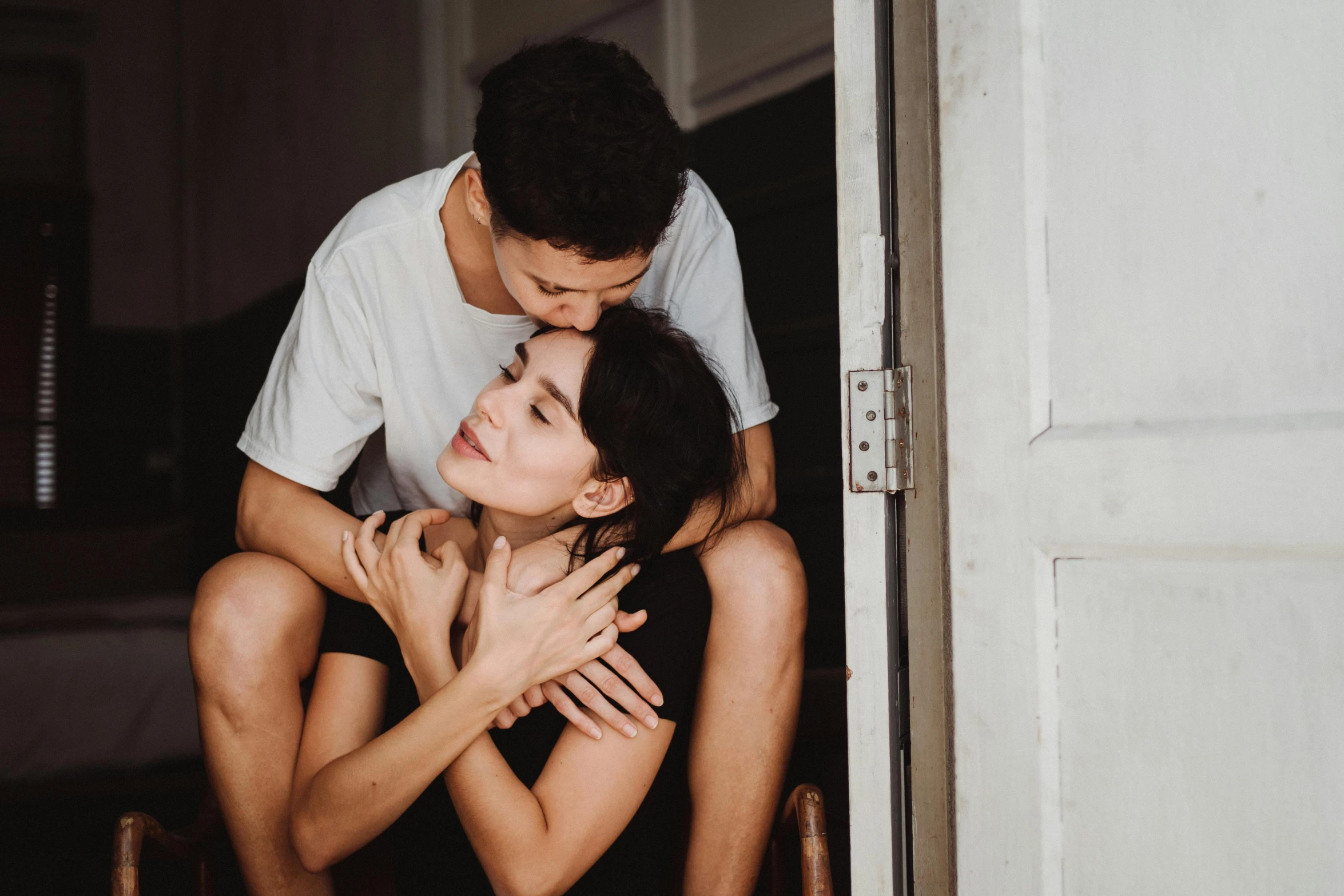 a woman is sitting with her arm around a man while he is hugging her