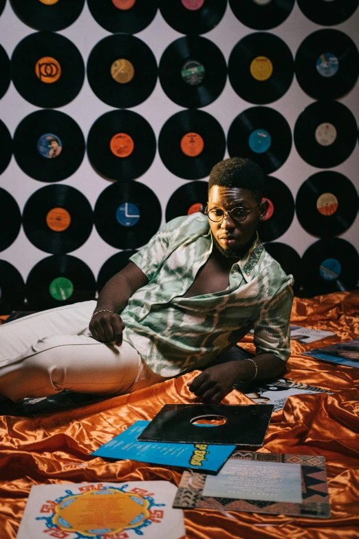 a man sitting on top of a bed next to record records