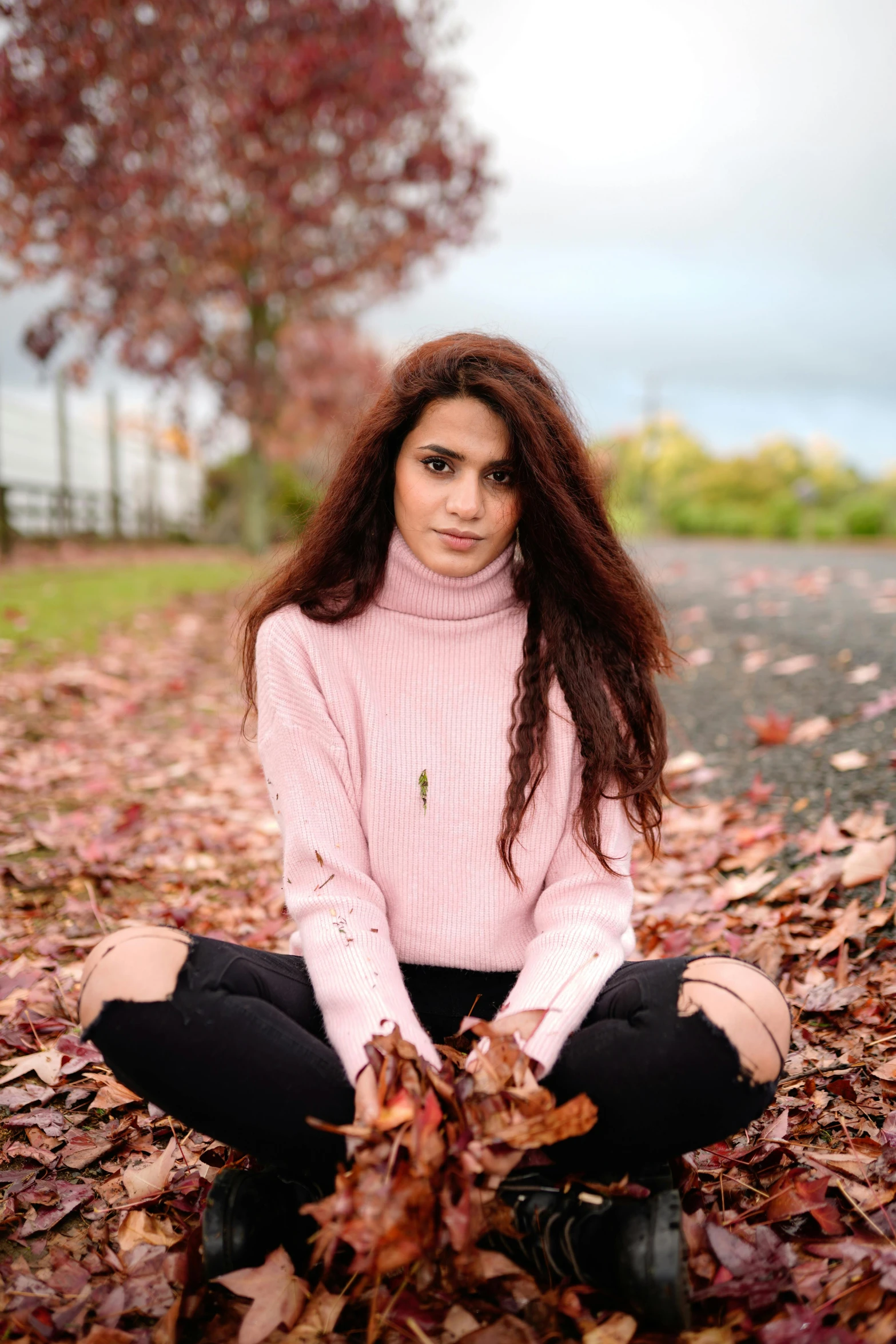 a girl with brown hair is sitting in leaves