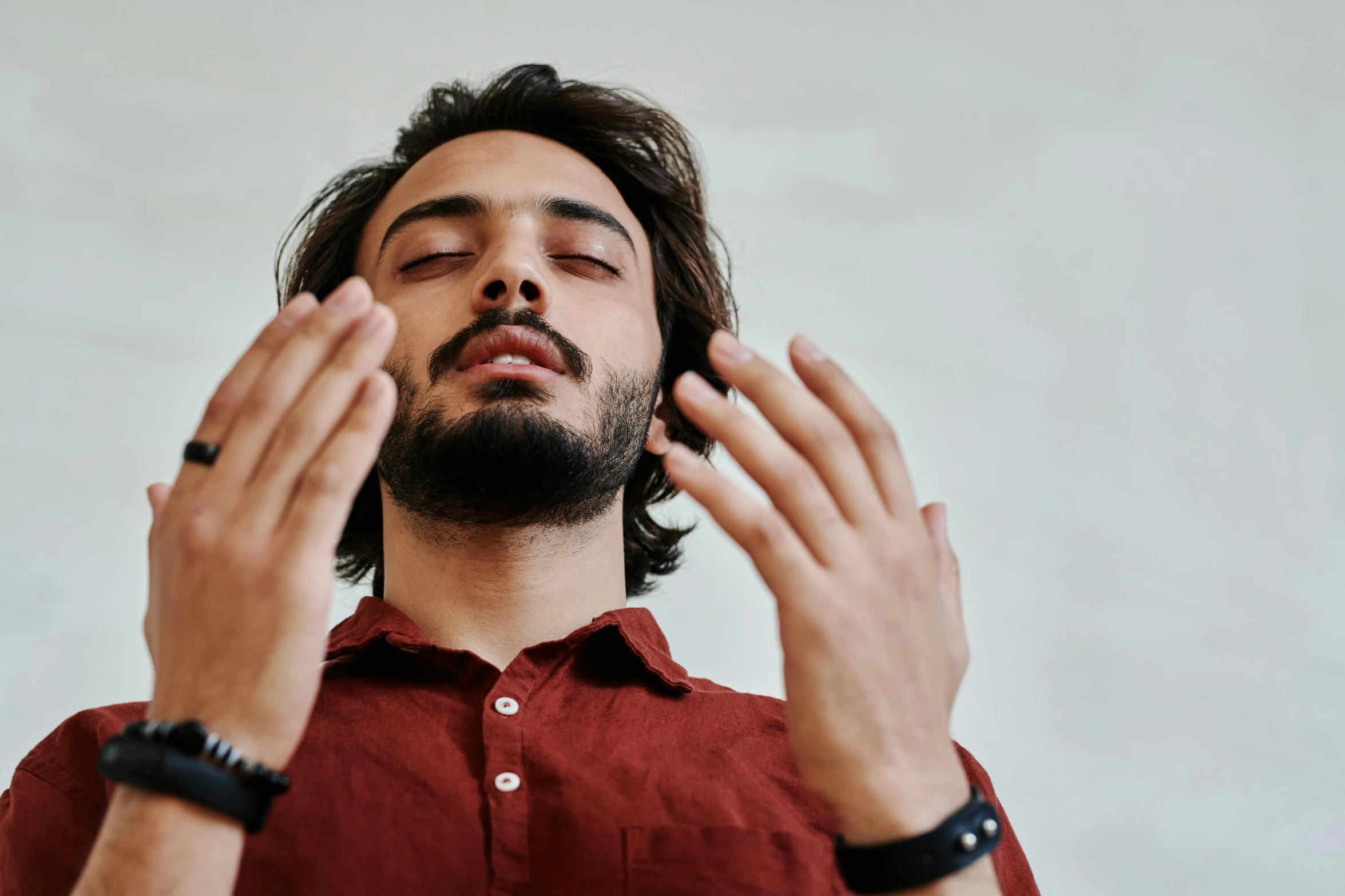 a man in red is holding his hands up and his eyes closed