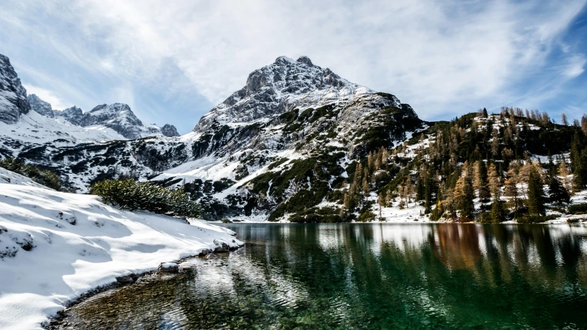 snowy mountain range above lake surrounded by snow covered mountains