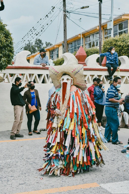 a large, colorful figure made of paper sits outside while pographers take pictures