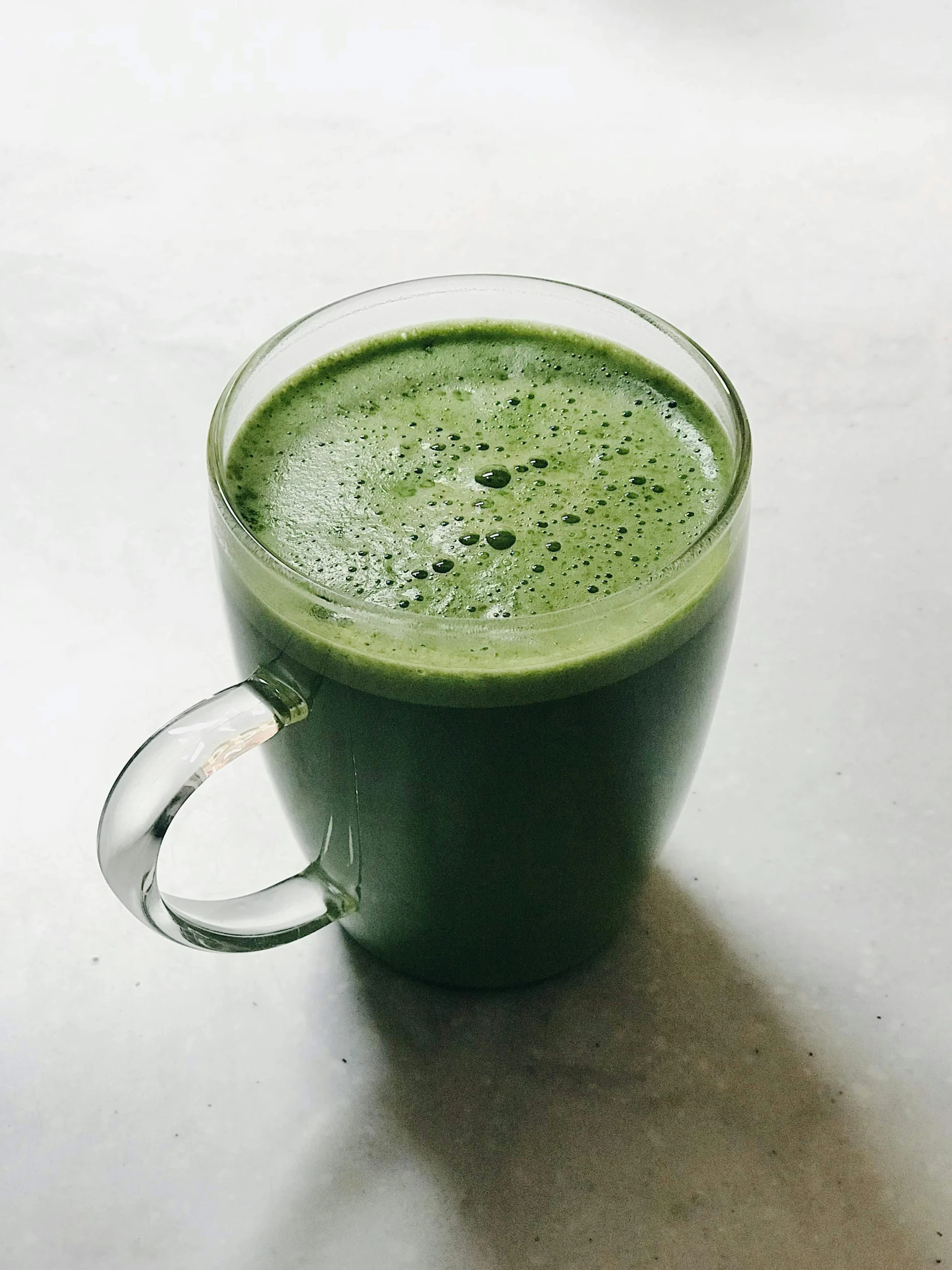 a glass cup full of green liquid with a spoon