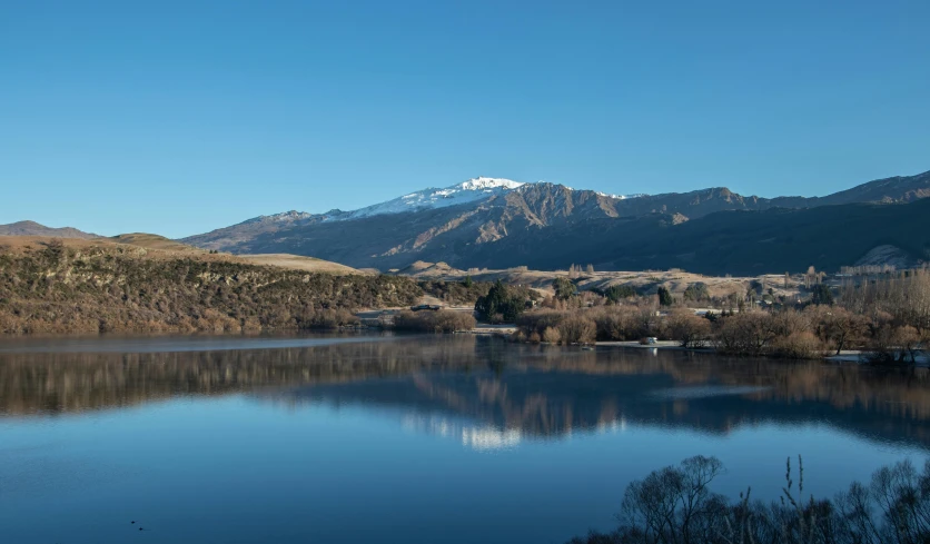 the water is clear and still reflecting the mountain scenery