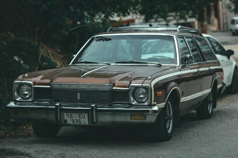 an older car sits parked on the side of a road