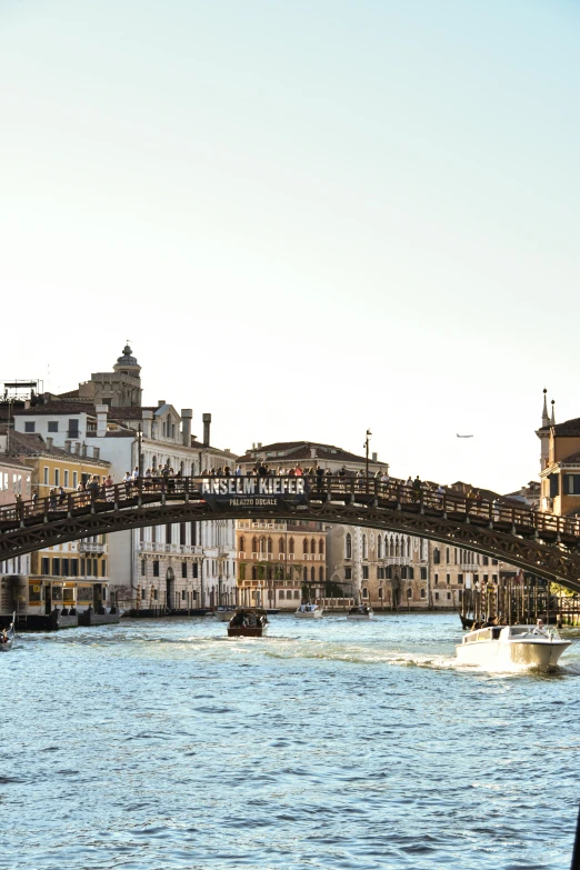 an old bridge with several tourists riding it and a boat driving on the water