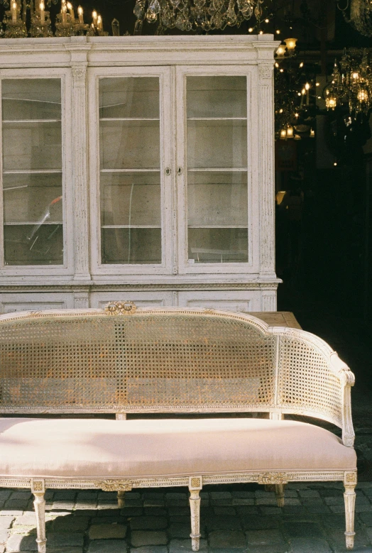 a white bench with a decorative armrest on a sidewalk