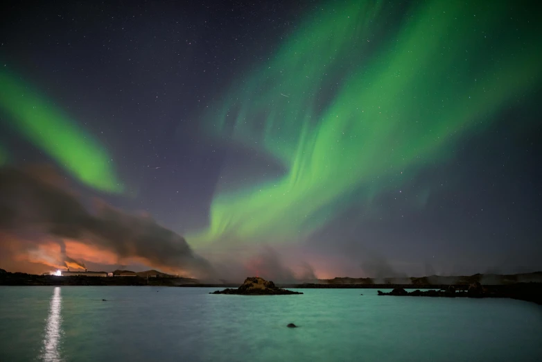 the green and purple lights are lit up over the water