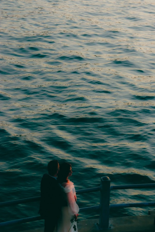 a couple emcing on a bridge overlooking a large body of water