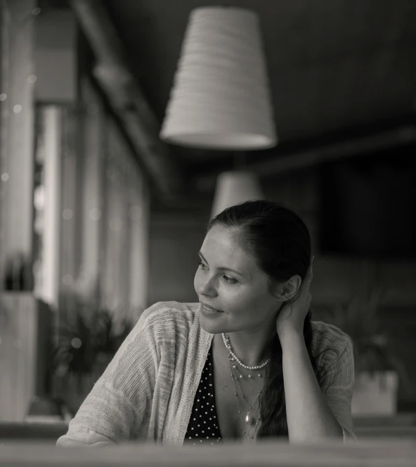 black and white pograph of woman sitting at table in restaurant