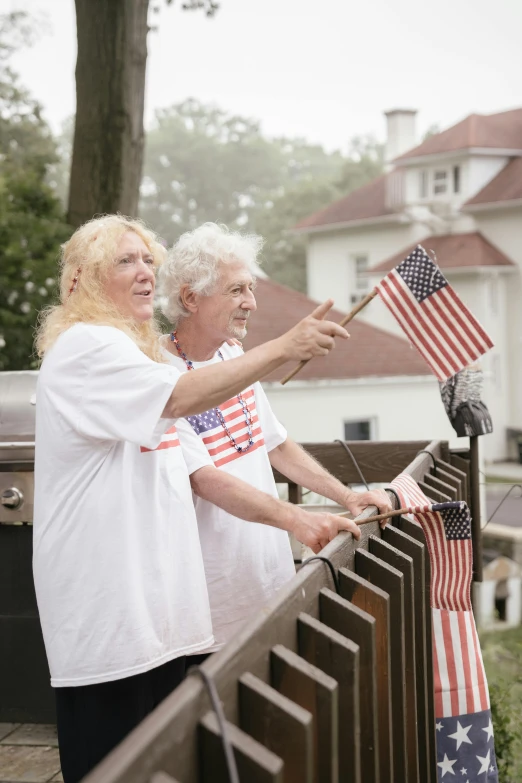 two women are looking at a fence that has an american flag in it