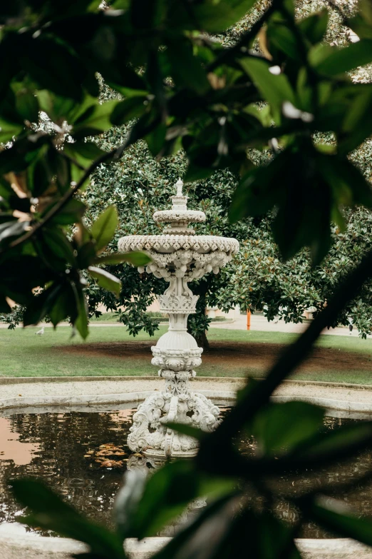 a large white water fountain sitting below some trees