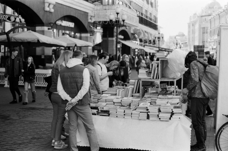 many people walking and a book stand in a street