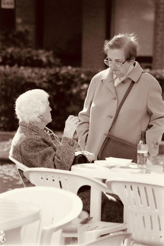 an elderly person holding the hand of an elderly person sitting at a table