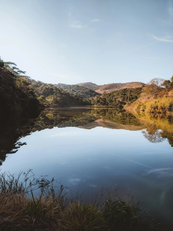 a beautiful lake sits surrounded by hills and trees