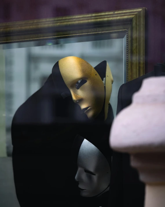 a black and gold mask is placed in front of a framed image