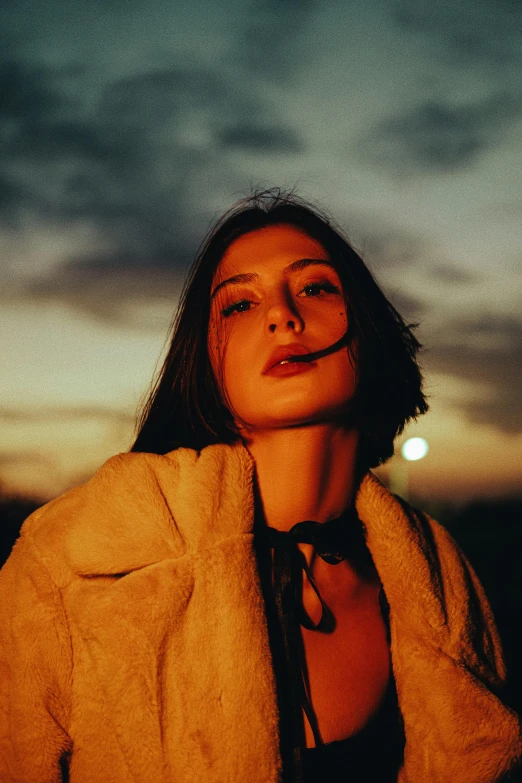 a woman looking upwards while standing against the evening sky