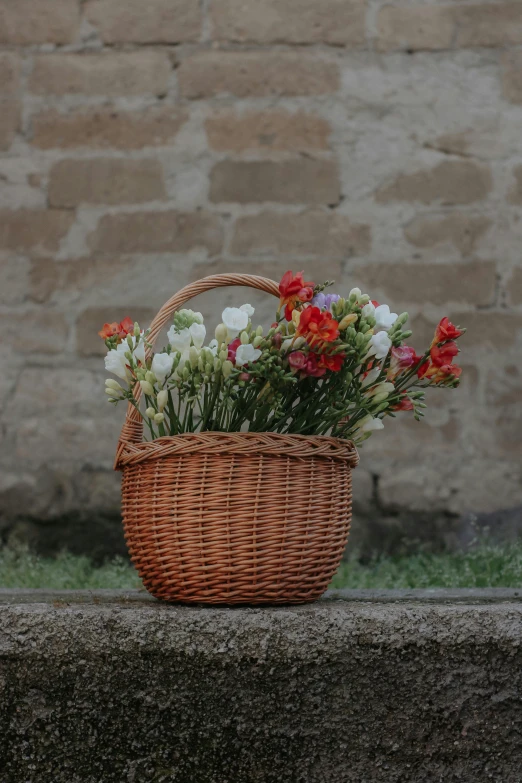 basket sitting on ledge with flowers in it