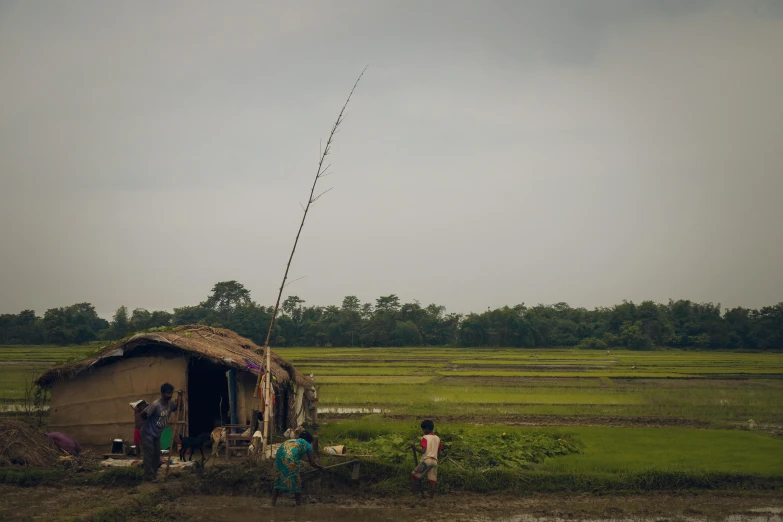 some people are walking outside of a hut in the grass