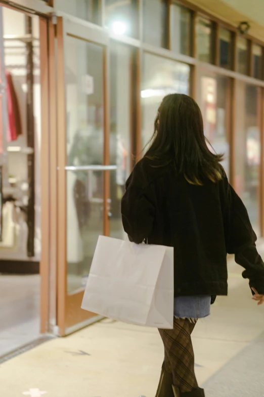 a woman carrying shopping bags walks by the storefront of a building