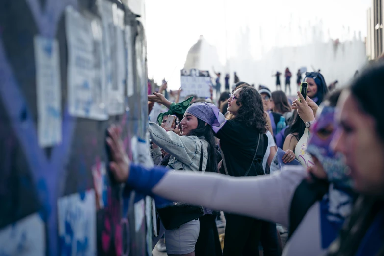 a crowd of women are standing together holding up their hands