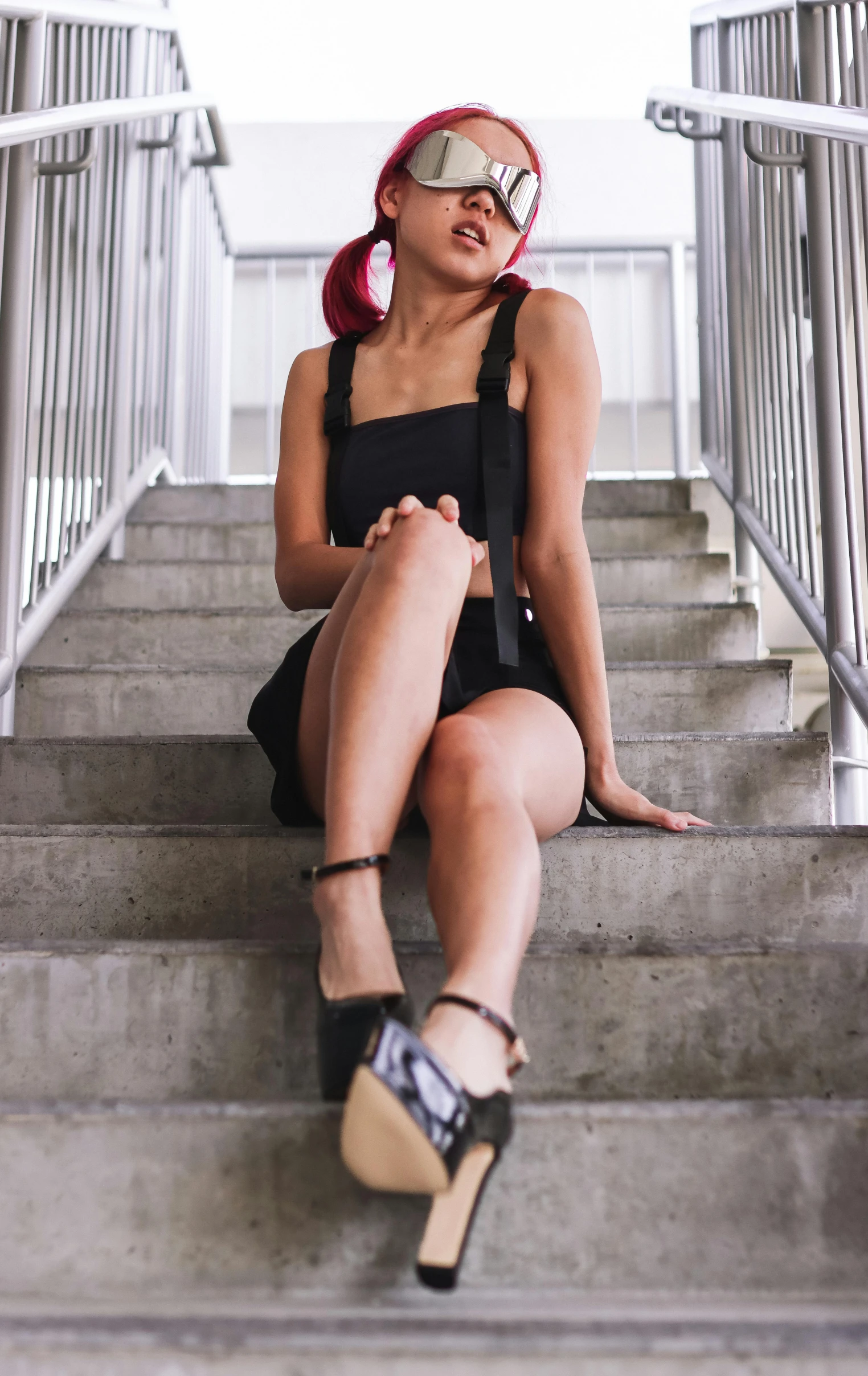 a woman sitting on a flight of steps wearing sunglasses