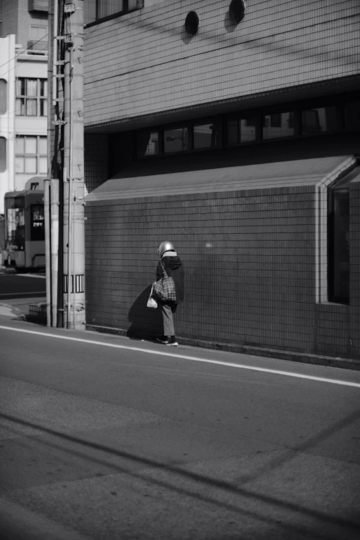 man sitting on the curb next to a wall in front of an apartment building