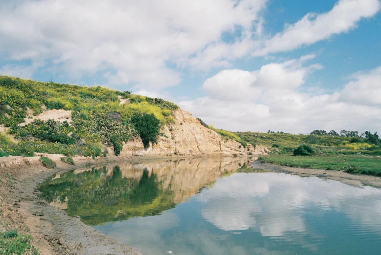 a hill and water with a cloudy sky